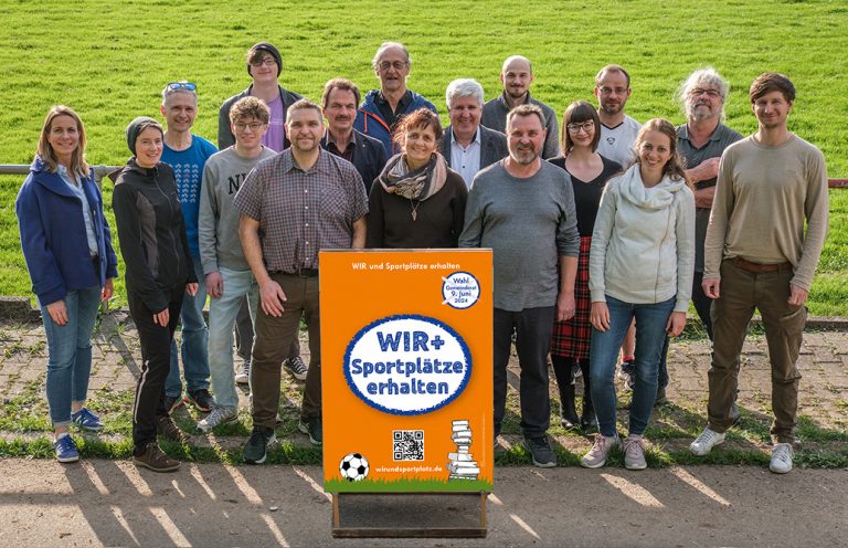 Ein Gruppenbild der Liste WIR und Sportplätze erhalten. Es zeigt lächelnde Menschen vor dem Sportplatz VfL Post in der Esslinger Pliensauvorstadt.